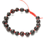 bratara pentru copii din chihlimbar negru cu snur rosu pe fundal alb