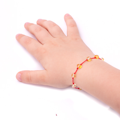 bratara chihlimbar galben cu snur rosu pe mana bebelus