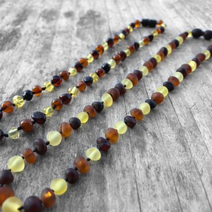 2 coliere chihlimbar multicolor mat si lucios expus pe fundal din lemn