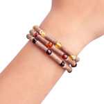 imagine cu 3 bratari din lemn de alun canadian si chihlimbar baltic expuse pe mana de copil