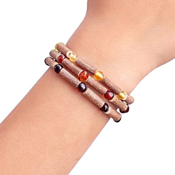 imagine cu 3 bratari din lemn de alun canadian si chihlimbar baltic expuse pe mana de copil