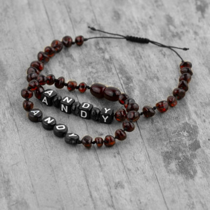 set 2 bratari tata baiat din chihlimbar baltic personalizate cu nume expuse pe fundal din lemn - Liniste si somn linistit pentru toata familia