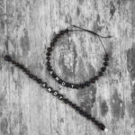 set bratari copil adult din chihlimbar negru personalizate cu nume expuse pe fundal de lemn