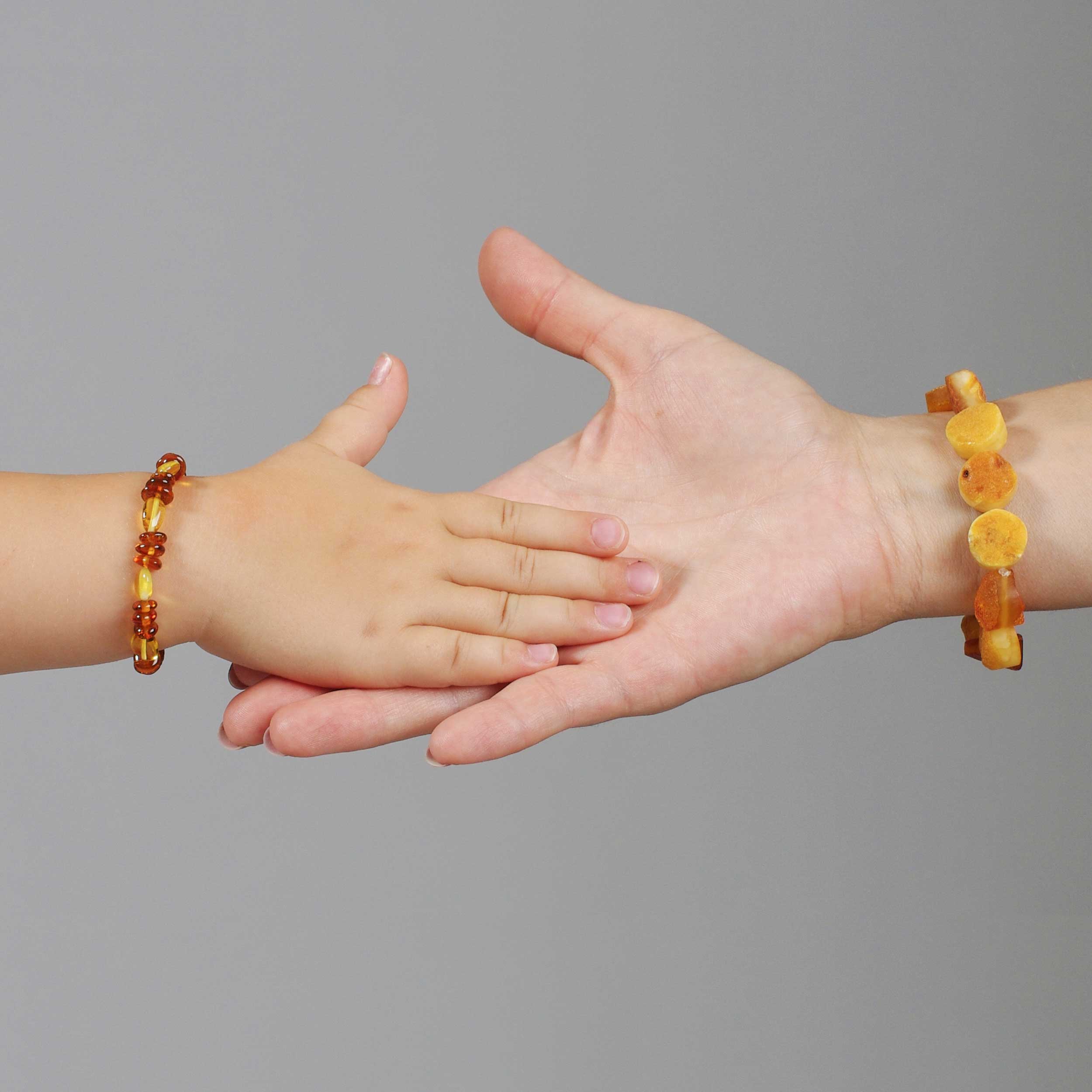 Doua maini, mamă și copil care poarta set bratari din chihlimbar