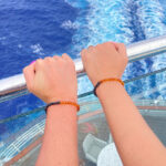 Set de brățări din chihlimbar pentru cuplu, purtate pe mâini, surprinse într-un moment de vacanță