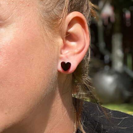 Cercei din chihlimbar în formă de inimă, culoare negru nuanță cireș, cu închizătoare fluturaș din argint 925, purtați de un model.