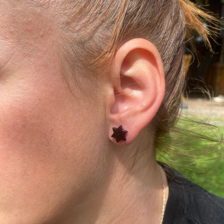 Doamnă purtând cercei în formă de stea din chihlimbar, cu închizătoare din argint, la ureche. Cerceii strălucesc, evidențiind frumusețea naturală a chihlimbarului și eleganța argintului.