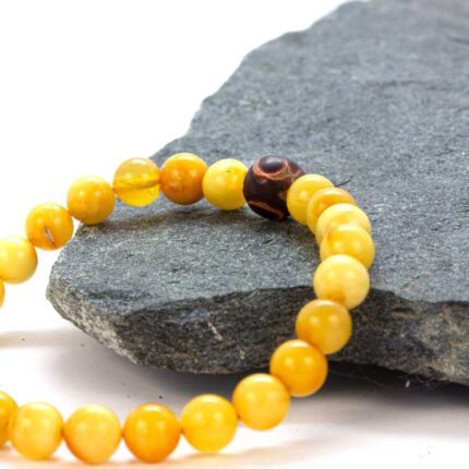 Brățară unisex din chihlimbar baltic și piatră Dzi agată – accesoriu natural pentru protecție și echilibru energetic, format din mărgele rotunde din chihlimbar galben și o piatră tibetană Dzi cu model tradițional.