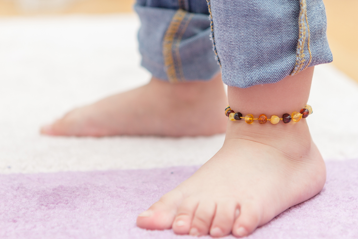 landscape copil in picioare purtand o bratara de picior/glezna din chihlimbar 